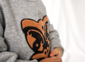 Close-up of Wheku Chenille Appliqué on Grey Crew Neck Sweatshirt